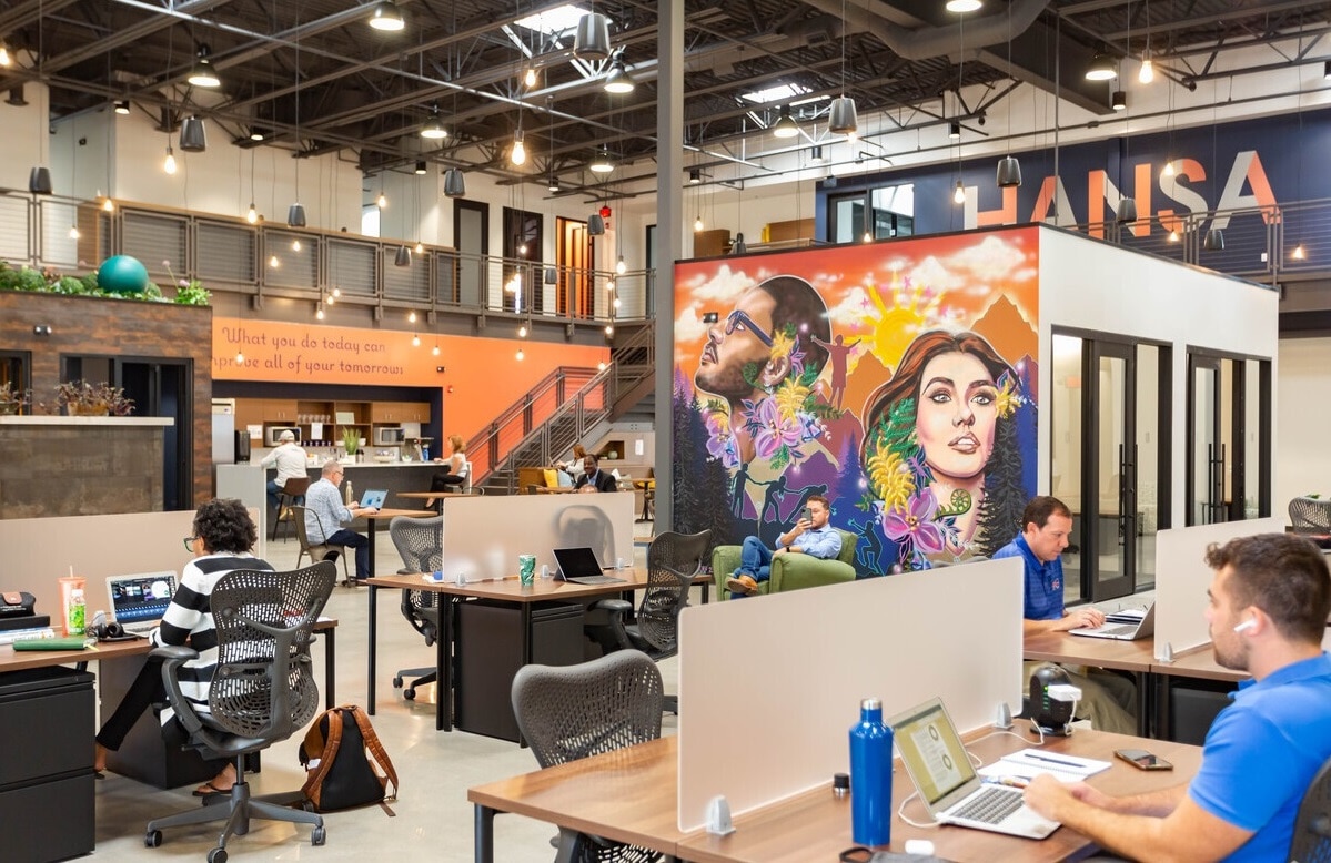 przestronne nowoczesne biuro coworkingowe z ludźmi pracującymi przy biurkach i laptopach