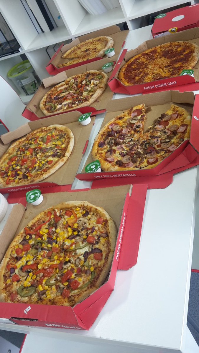 stosy pudeł z pizzą na stole obok napojów i przystawek