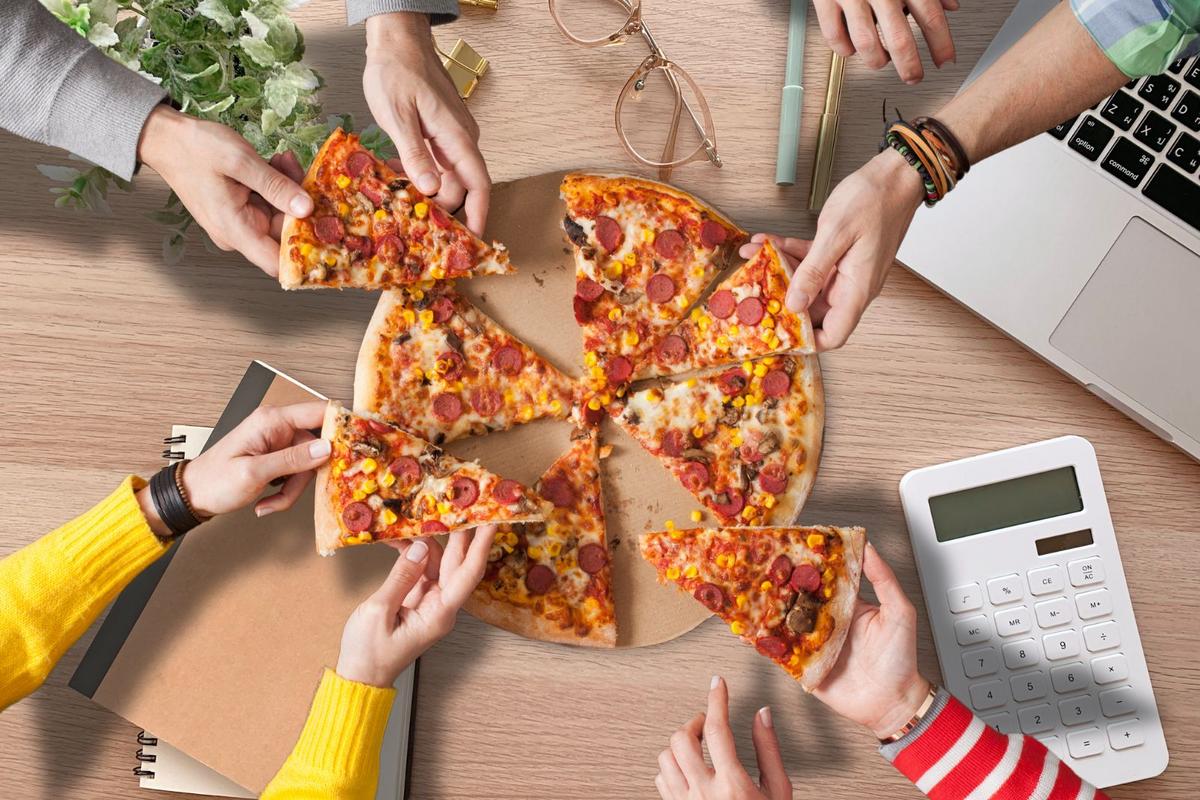 zespół biurowy radośnie je pizzę przy stole w sali konferencyjnej